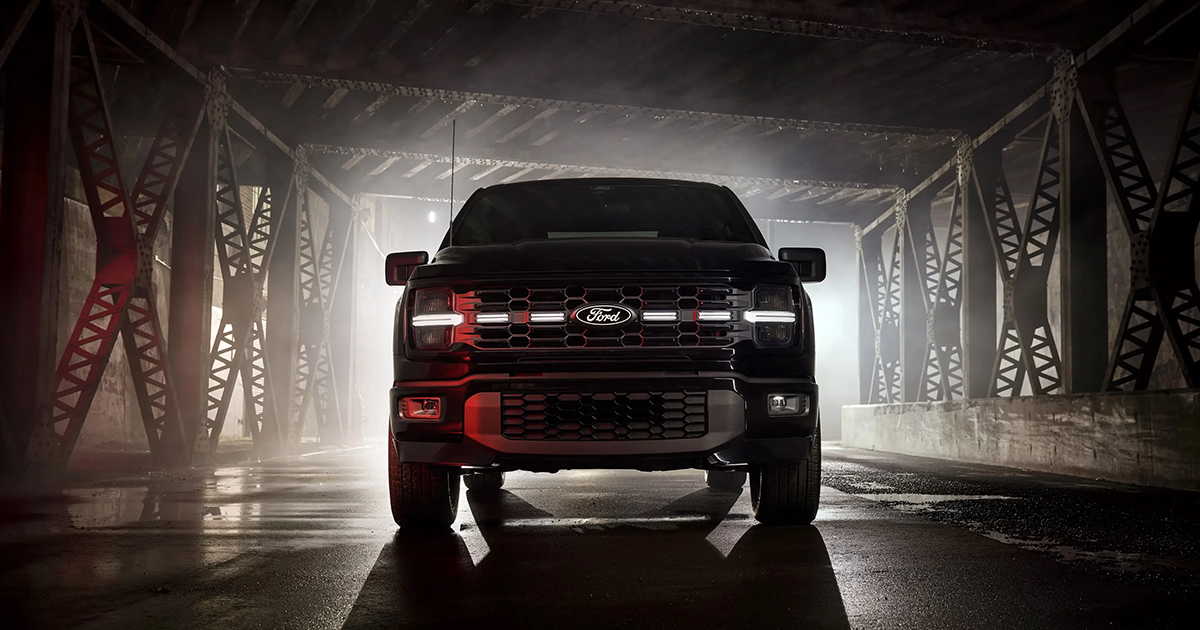 Black Ford F-150 pickup truck with red accents, front view on misty bridge, showcasing aggressive grille design and headlights