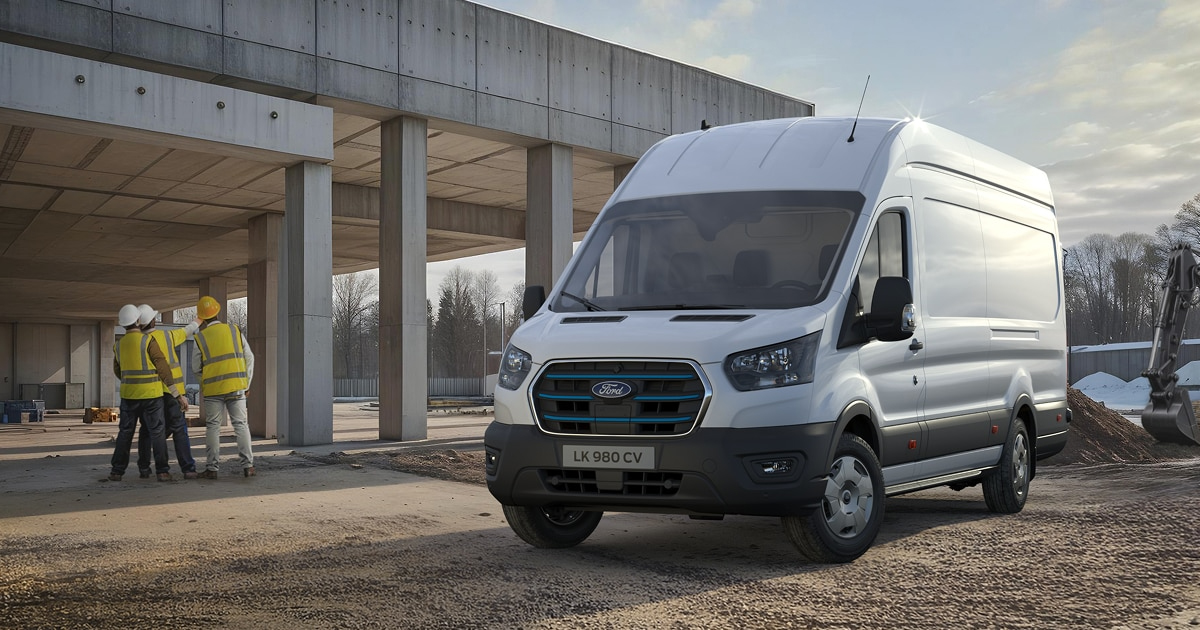 White Ford E-Transit electric van parked at construction site with workers in hard hats in background
