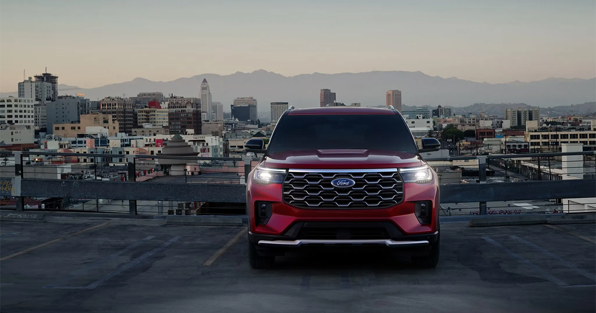 Red Ford Explorer SUV parked on rooftop parking lot with Los Angeles downtown skyline and mountains in background