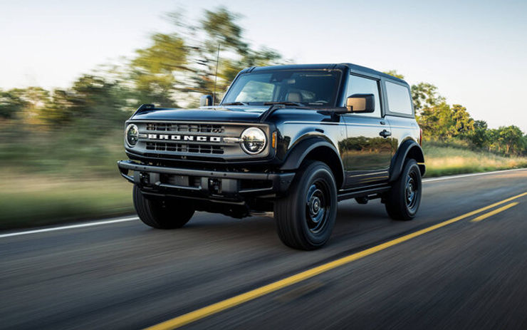 Black Ford Bronco two-door SUV driving on highway with blurred trees in background during daytime