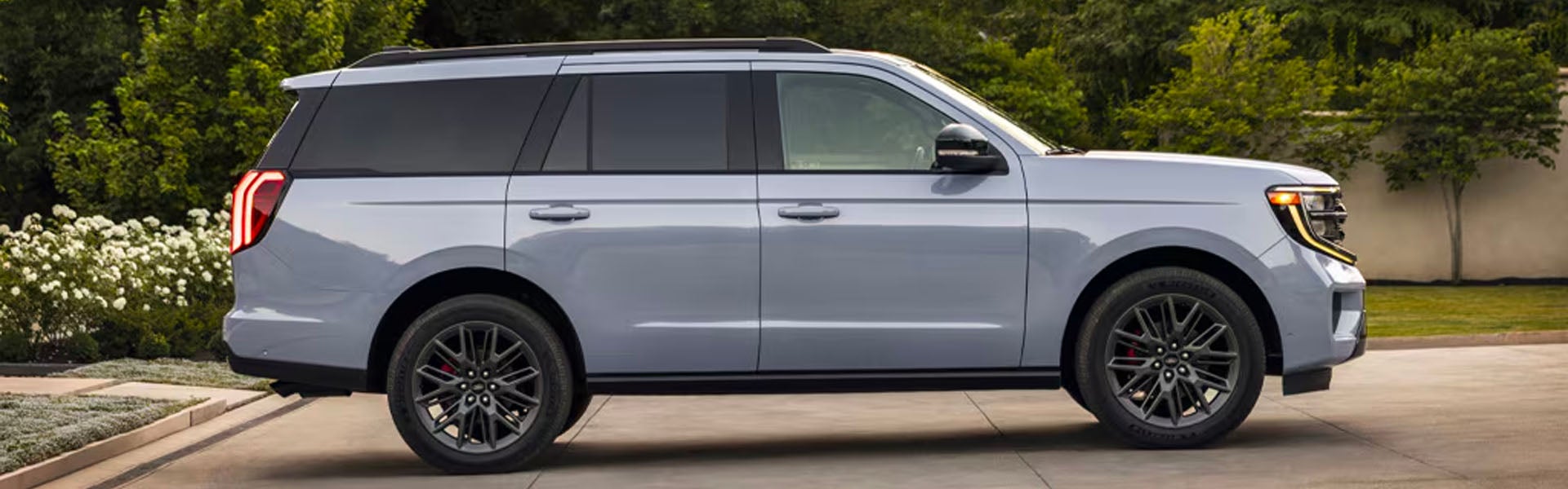 A large, light blue or grey SUV, likely a Ford Expedition, parked outside