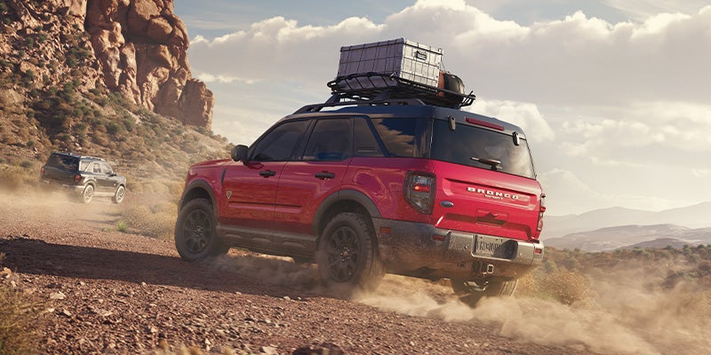 Red Bronco Sport kicks up dust on a desert trail with other SUVs