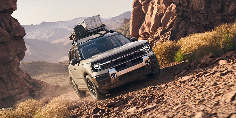 Light gray Bronco Sport drives down a steep, rocky desert decline