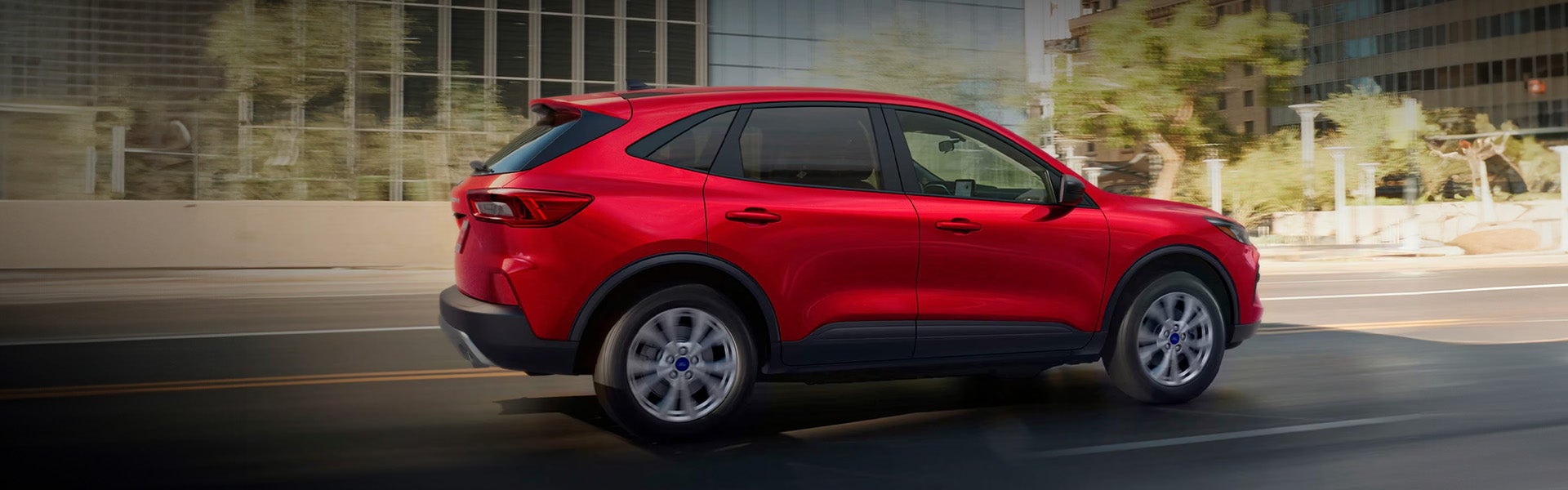 A bright red Ford Escape driving on a city street.